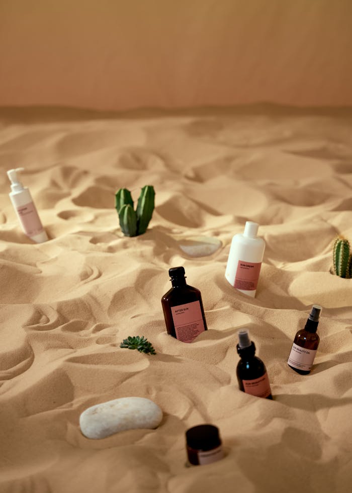 Skincare products artfully displayed on sand with a desert theme.